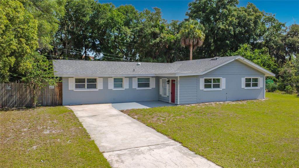 A single-story gray house with a red front door and a concrete driveway — 807 CHEROKEE CIRCLE, SANFORD, FL