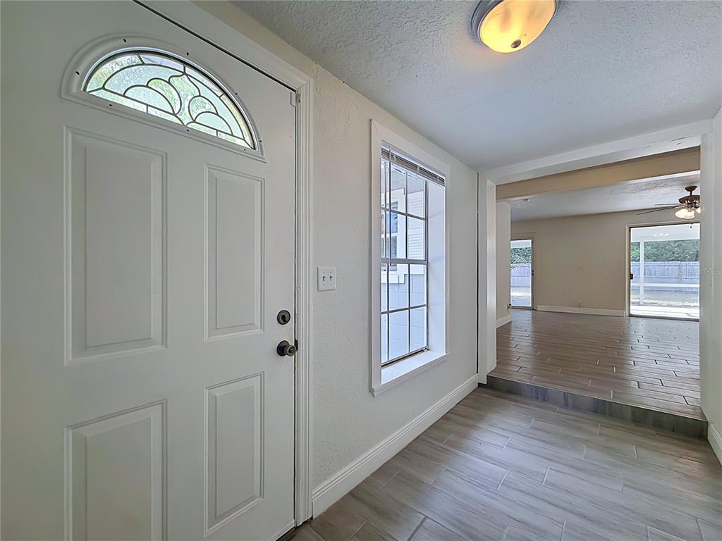An entryway with a white front door, a window, and wood-look tile flooring — 807 CHEROKEE CIRCLE, SANFORD, FL