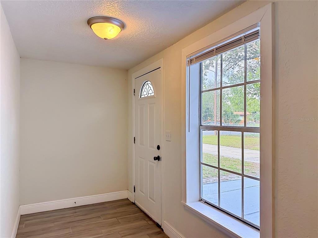 An entryway features wood-look flooring, a white front door, and a large window — 807 CHEROKEE CIRCLE, SANFORD, FL