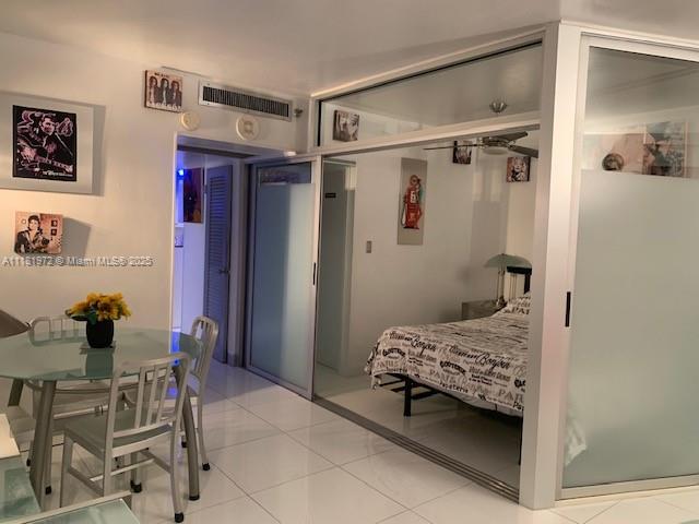 A dining area with a glass table sits beside a bedroom enclosed by sliding glass doors — 100 LINCOLN RD # 1509, Miami Beach FL 33139, MIAMI BEACH, FL
