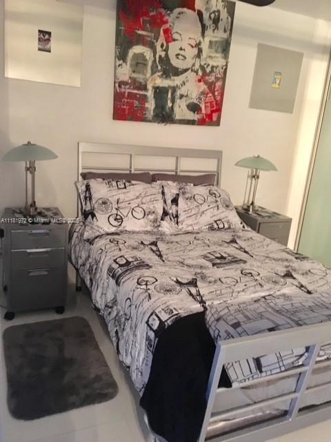 A bedroom features a bed with patterned bedding, two nightstands with lamps, and wall art — 100 LINCOLN RD # 1509, Miami Beach FL 33139, MIAMI BEACH, FL
