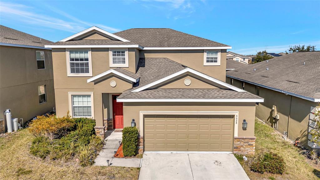 A two-story suburban house with a tan stucco exterior, brown roof, and attached garage — 4628 CORTLAND DRIVE, DAVENPORT, FL