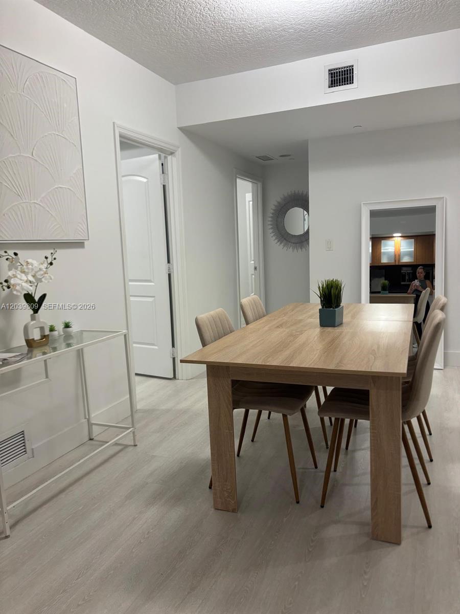 A dining area features a light wood table, upholstered chairs, and a glass console table — 601 NE 23rd St # 806, Miami FL 33137, MIAMI, FL