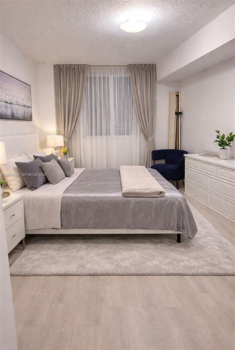 A bedroom features a bed with grey bedding, a white dresser, and a blue chair — 601 NE 23rd St # 806, Miami FL 33137, MIAMI, FL