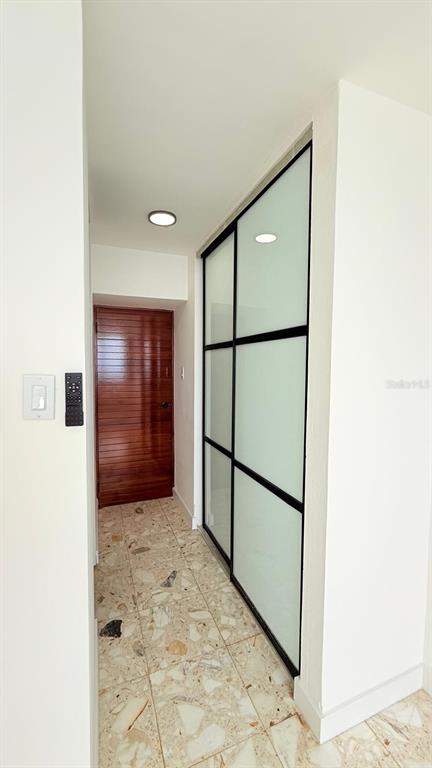 A hallway features terrazzo flooring, a wooden door, and a sliding glass closet with black frames — 0 ASHFORD AVE UNIT 1207, CONDADO, PR