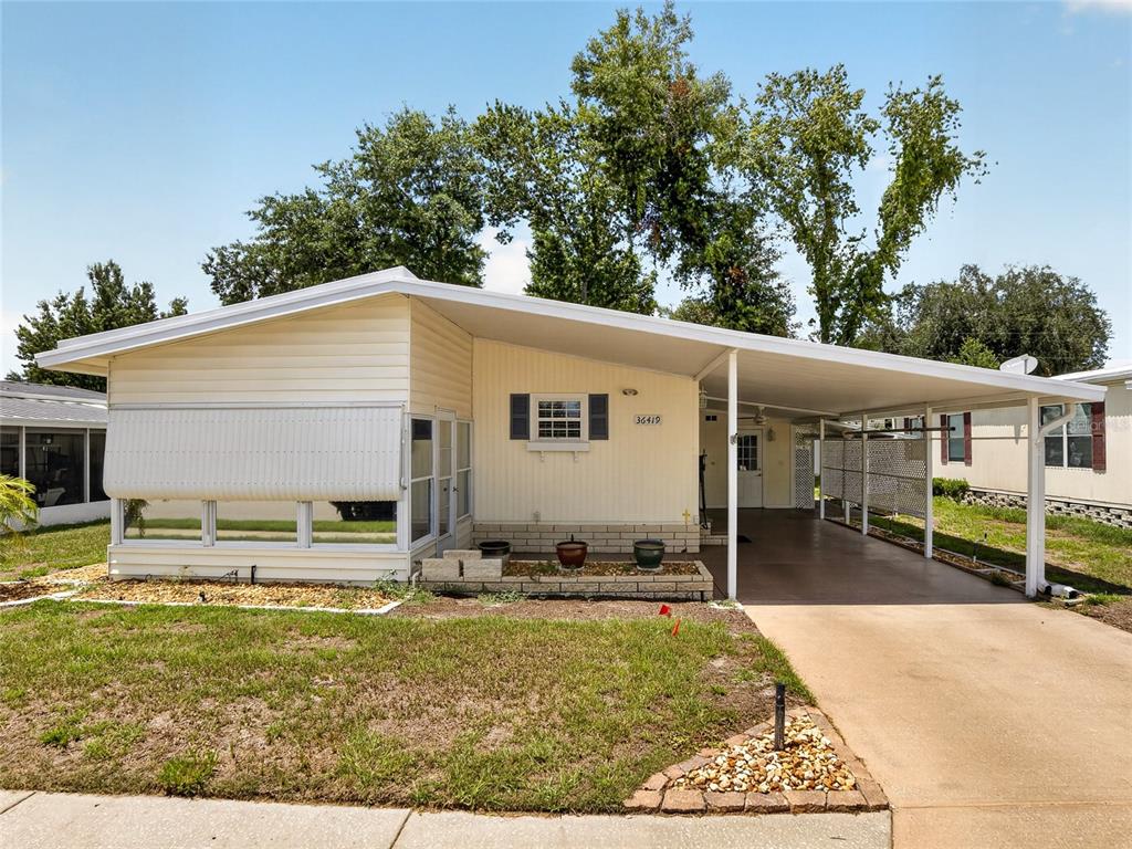 A single-story mobile home with a carport, a front porch, and a concrete driveway — 36419 BONNEY DRIVE, ZEPHYRHILLS, FL