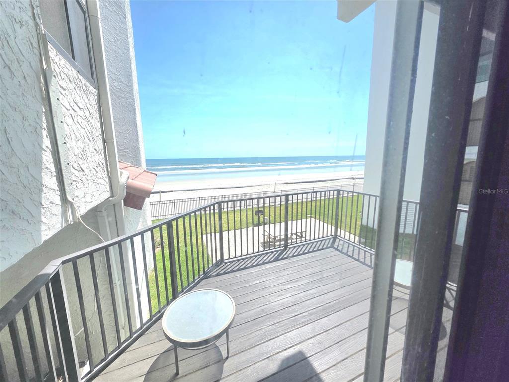 A wooden balcony overlooks a sandy beach and the ocean behind a metal railing — 3001 S ATLANTIC AVENUE UNIT 300, NEW SMYRNA BEACH, FL