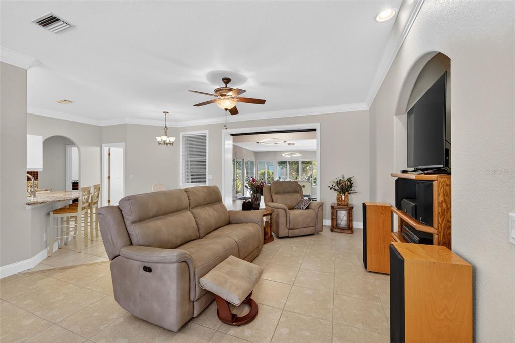 A living room with beige tile floors, a tan sofa, and a wall-mounted television — 7888 EVINRUDE AVENUE, NORTH PORT, FL