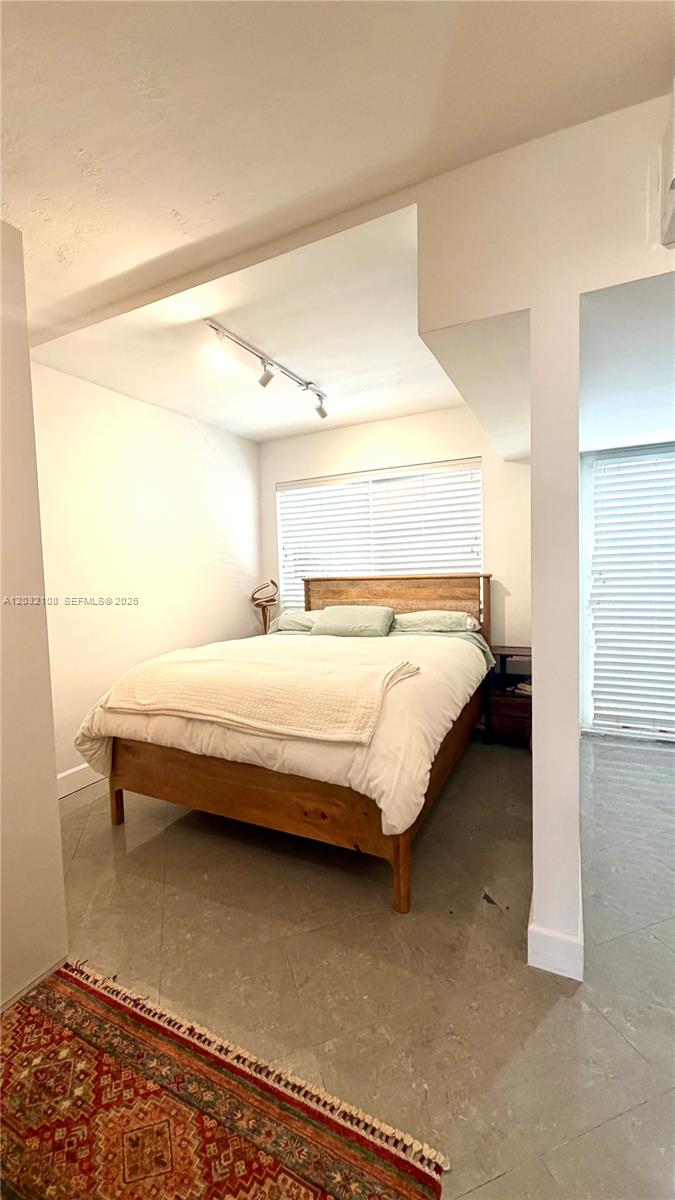 A bedroom features a wooden bed frame, tile flooring, and a patterned area rug — 626 Meridian Ave # 5, Miami Beach FL 33139, MIAMI BEACH, FL