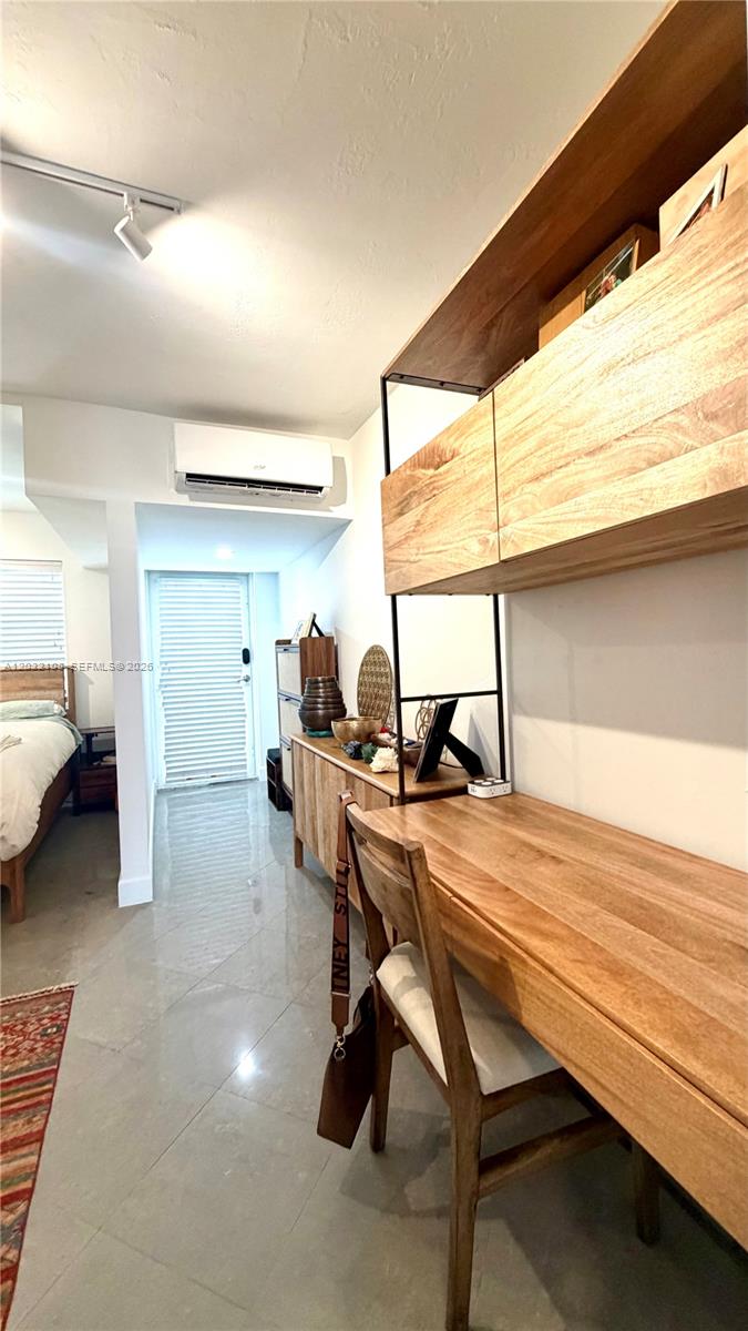 A bedroom features a wooden desk, shelving unit, tile flooring, and a wall-mounted air conditioner — 626 Meridian Ave # 5, Miami Beach FL 33139, MIAMI BEACH, FL