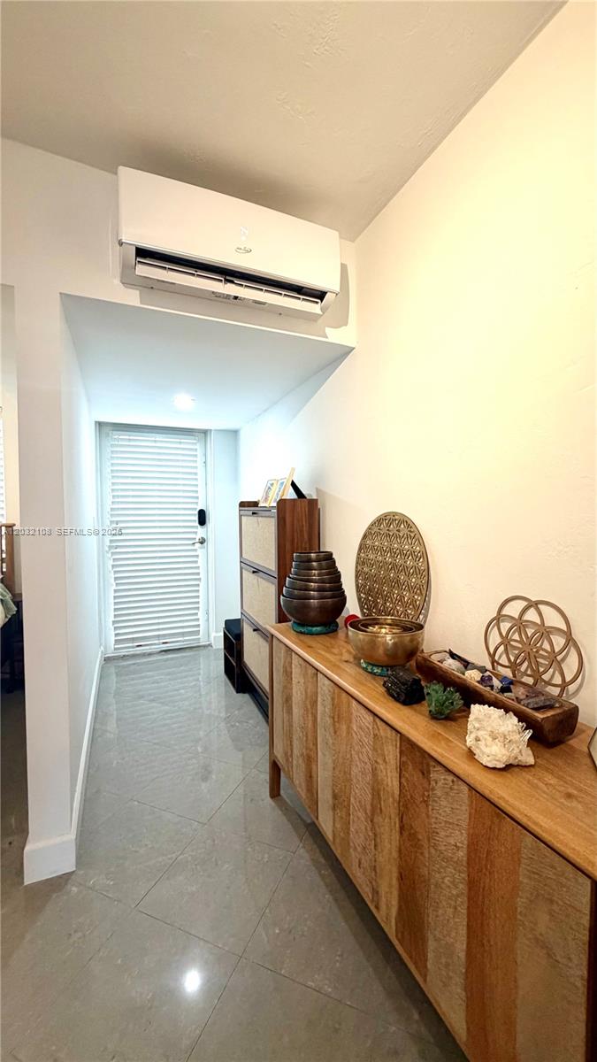 A hallway features a wooden console table, a wall-mounted air conditioner, and tiled flooring — 626 Meridian Ave # 5, Miami Beach FL 33139, MIAMI BEACH, FL