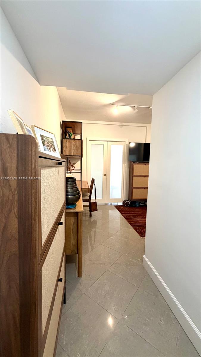 A hallway with light tile flooring leads toward a room with a desk and television — 626 Meridian Ave # 5, Miami Beach FL 33139, MIAMI BEACH, FL
