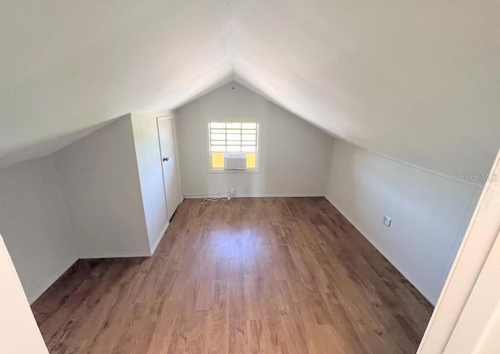 An attic bedroom features slanted ceilings, white walls, and wood-look flooring — 215 N BUENA VISTA DRIVE, LAKE ALFRED, FL