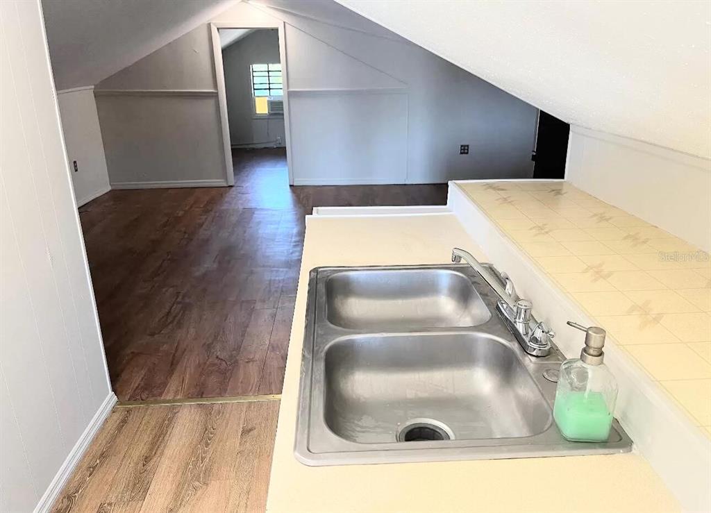 A double-basin stainless steel sink sits on a tiled counter in an attic room — 215 N BUENA VISTA DRIVE, LAKE ALFRED, FL