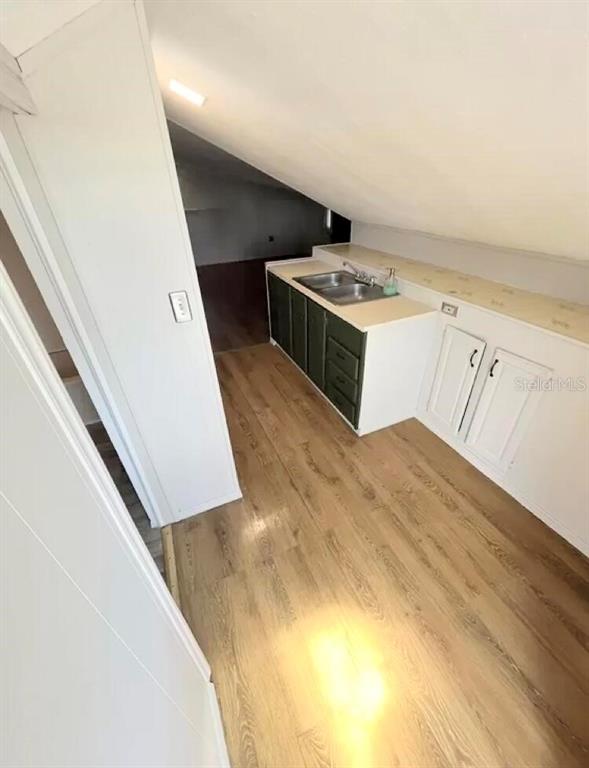 A kitchen area with a sloped ceiling, wood-look flooring, and green and white cabinetry — 215 N BUENA VISTA DRIVE, LAKE ALFRED, FL