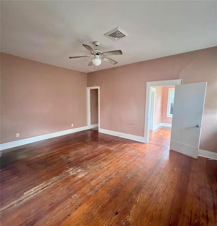 An empty room with pink walls, hardwood floors, a ceiling fan, and two doorways — 215 N BUENA VISTA DRIVE, LAKE ALFRED, FL