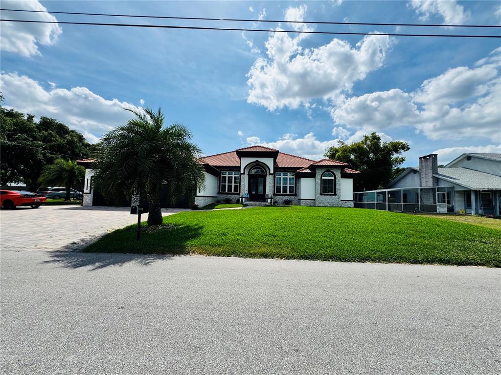 A single-story house with a tiled roof, stone facade, and a paved driveway — 803 LAKE JESSIE DR DRIVE, WINTER HAVEN, FL