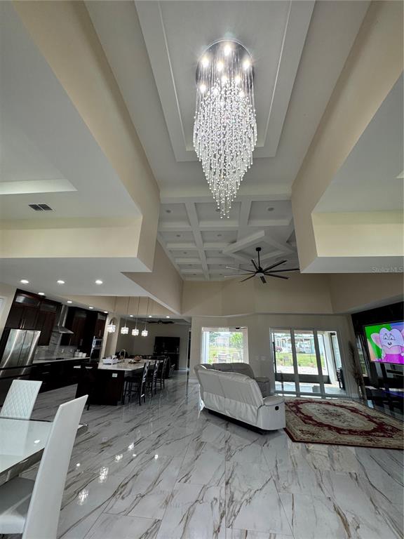 A spacious open-concept living area features a crystal chandelier, coffered ceiling, and marble flooring — 803 LAKE JESSIE DR DRIVE, WINTER HAVEN, FL