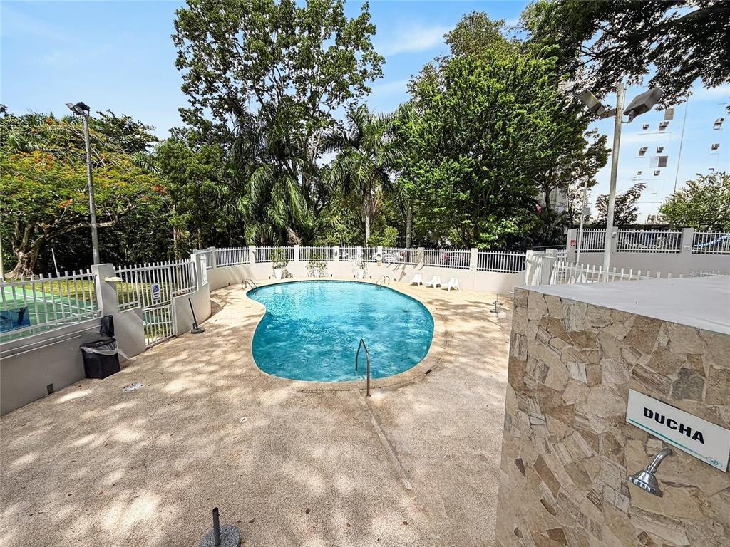 An outdoor swimming pool with a stone-tiled shower area and surrounding white metal fencing — 444 CONDOMINIO DE DIEGO UNIT 1503, SAN JUAN, PR