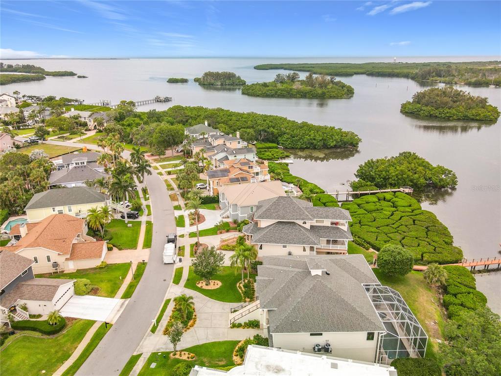 An aerial view shows waterfront houses along a curved street near a bay and mangroves — 2021 NORTH POINTE ALEXIS DRIVE, TARPON SPRINGS, FL