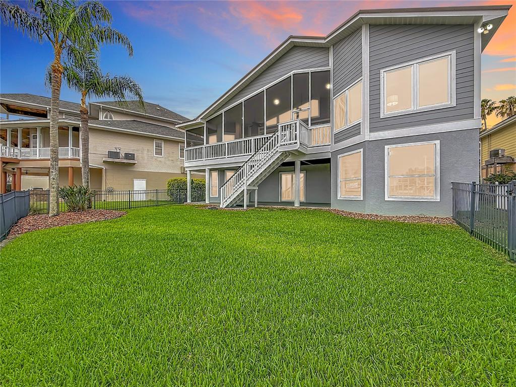 The exterior of a two-story gray house features a screened-in porch and a grassy backyard — 2021 NORTH POINTE ALEXIS DRIVE, TARPON SPRINGS, FL