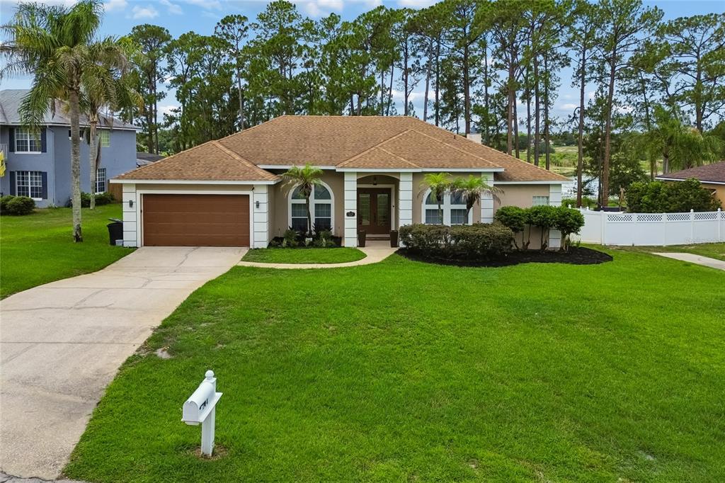 A single-story house with a brown roof, tan stucco exterior, and a two-car garage — 114 GLEN ABBEY LANE, DEBARY, FL