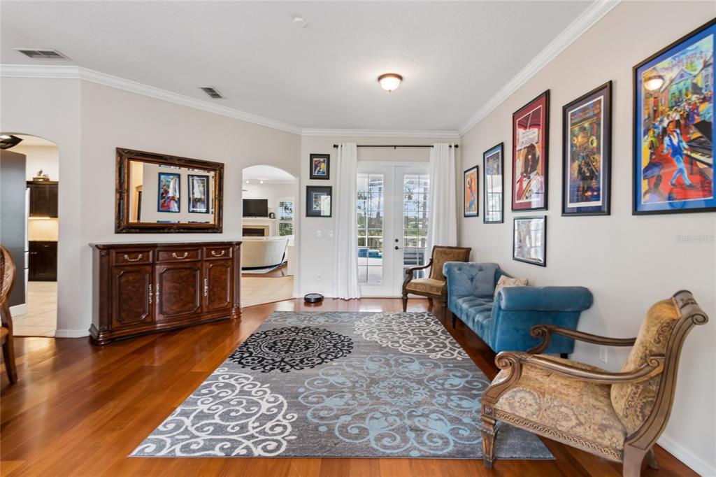 A living room features hardwood floors, a patterned area rug, blue sofa, and framed artwork — 114 GLEN ABBEY LANE, DEBARY, FL