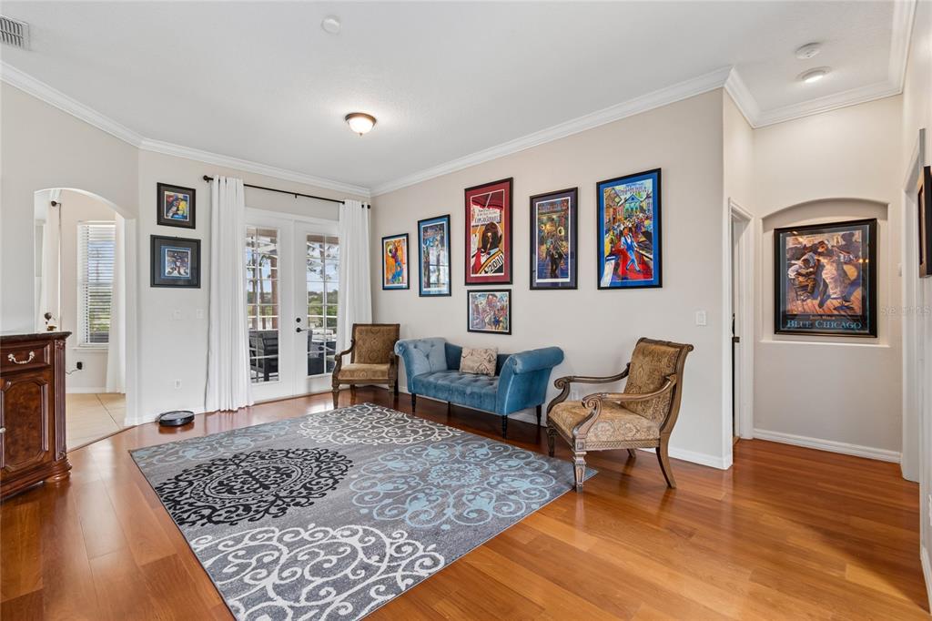 A living room features hardwood floors, a patterned area rug, blue sofa, and framed artwork — 114 GLEN ABBEY LANE, DEBARY, FL