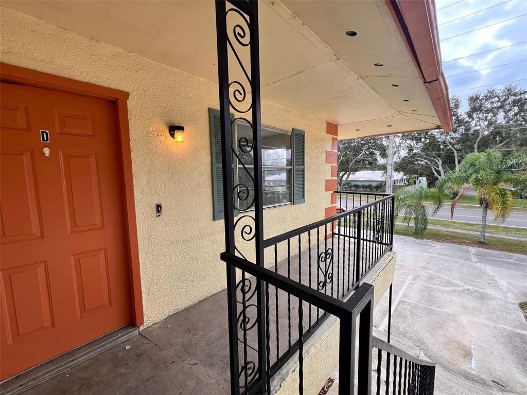 An exterior view of an apartment balcony with a metal railing and a door marked D — 2190 KNOX MACRAE DRIVE UNIT D, TITUSVILLE, FL