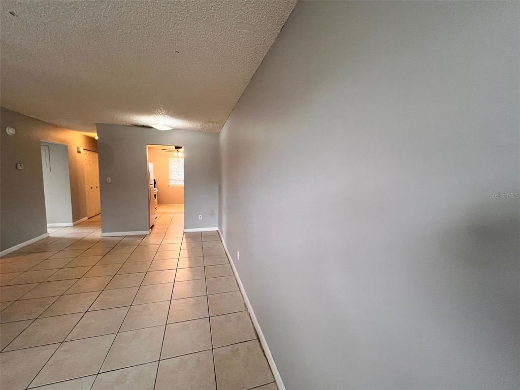 A room with light-colored tile flooring and gray walls leads to a kitchen area — 2190 KNOX MACRAE DRIVE UNIT D, TITUSVILLE, FL