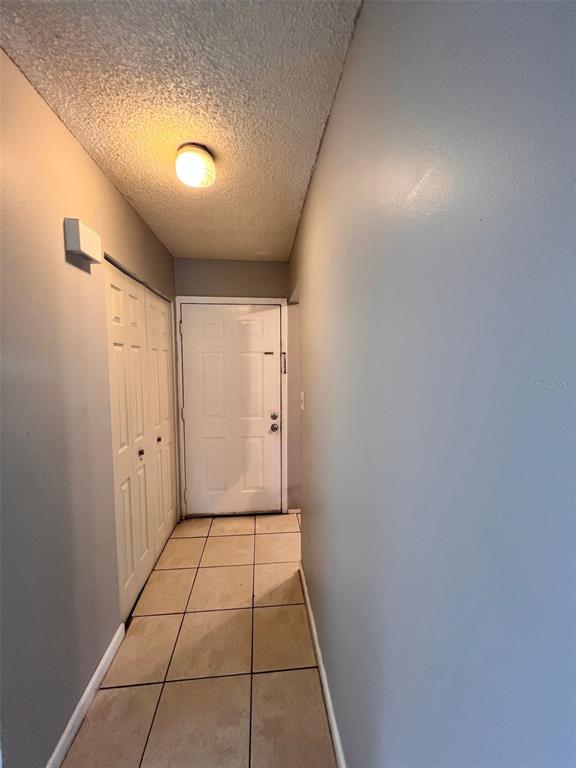 A hallway features light-colored tile flooring, gray walls, a white door, and a closet — 2190 KNOX MACRAE DRIVE UNIT D, TITUSVILLE, FL