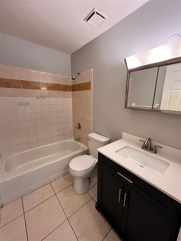 A bathroom features a white bathtub, a toilet, and a dark vanity with a sink — 2190 KNOX MACRAE DRIVE UNIT D, TITUSVILLE, FL
