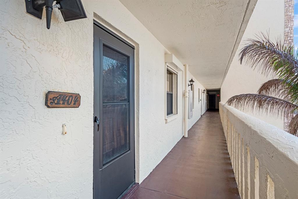 An exterior walkway leads to a dark-framed door marked with the number 404 — 1890 N ATLANTIC AVENUE UNIT A404, COCOA BEACH, FL