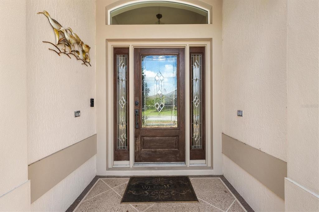 A front entryway features a wooden door with glass panels and a decorative metal bird sculpture — 1304 BRUNELL STREET, THE VILLAGES, FL