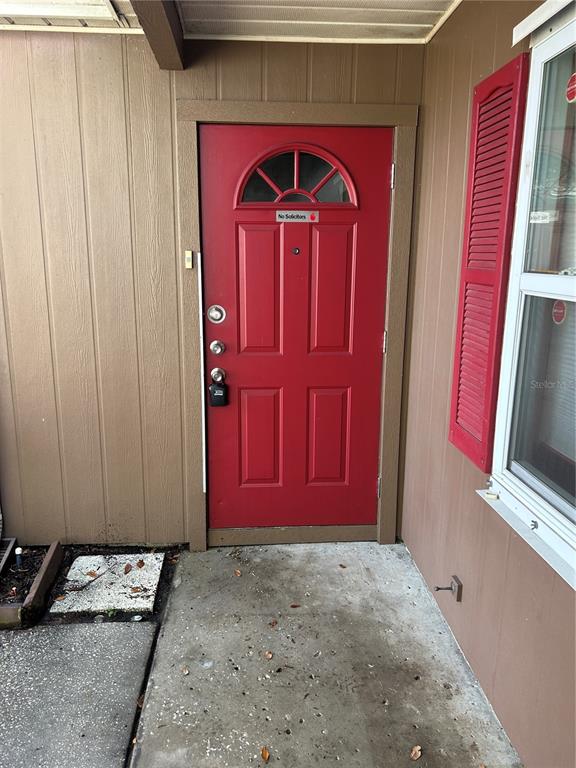 A red front door with a small window and a lockbox sits on a concrete porch — 515 S MATANZAS AVENUE, TAMPA, FL