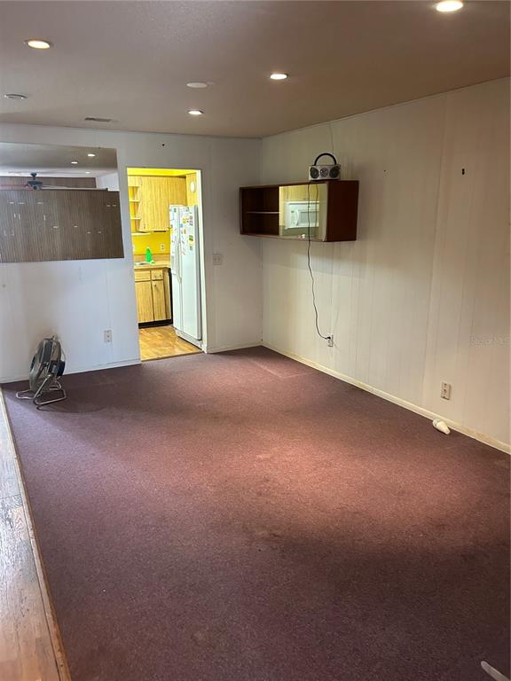 A room with dark carpet, white paneled walls, recessed lighting, and a wall-mounted wooden shelf — 515 S MATANZAS AVENUE, TAMPA, FL