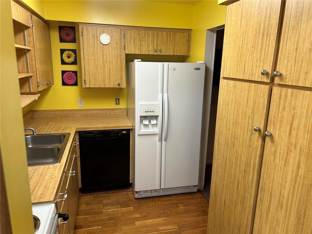 A kitchen features wood-grain cabinets, yellow walls, a black dishwasher, and a white refrigerator — 515 S MATANZAS AVENUE, TAMPA, FL