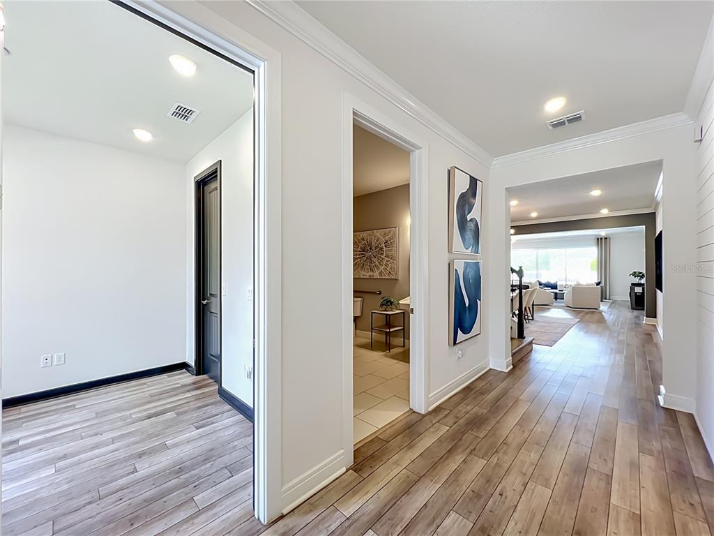 A hallway with wood-look flooring leads to a living area, a bathroom, and a room — 10774 PAHOKEE BEACH PLACE, ORLANDO, FL