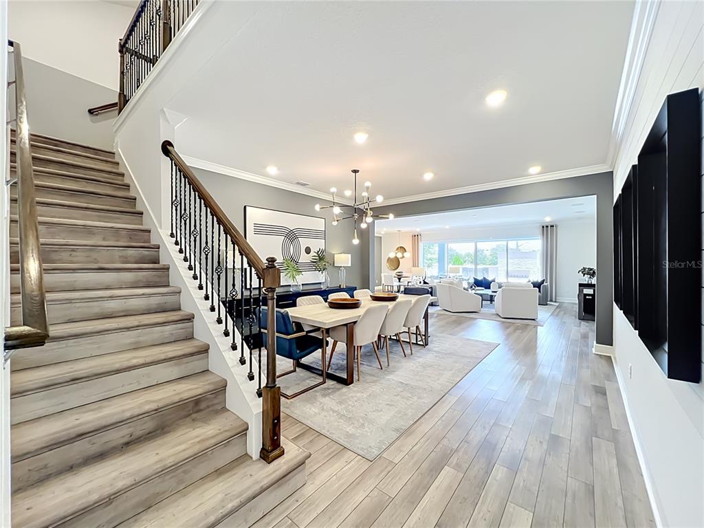 A staircase with wood treads leads to an open-concept dining area and living room — 10774 PAHOKEE BEACH PLACE, ORLANDO, FL