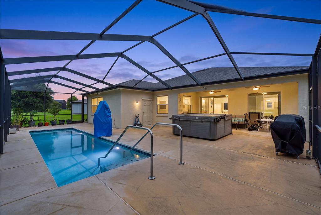 A screened-in patio features a swimming pool, a hot tub, and a covered seating area — 4419 BENT CREEK LANE, LEESBURG, FL