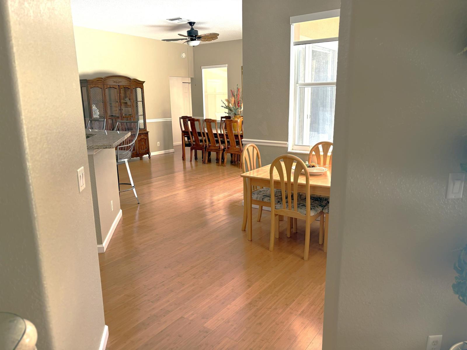A dining area and kitchen with hardwood floors, a wooden table, and a ceiling fan — 7611 N 140th Ave Avenue N, FL 33412, FL