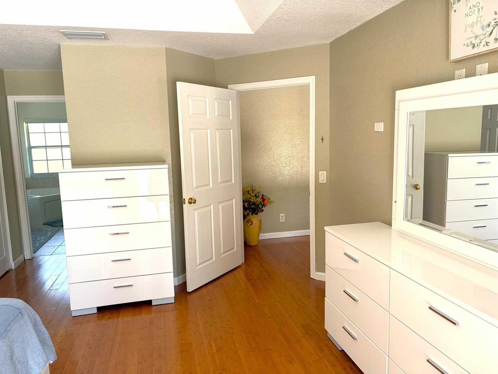 A bedroom features hardwood floors, two white dressers, and an open doorway to a bathroom — 7611 N 140th Ave Avenue N, FL 33412, FL