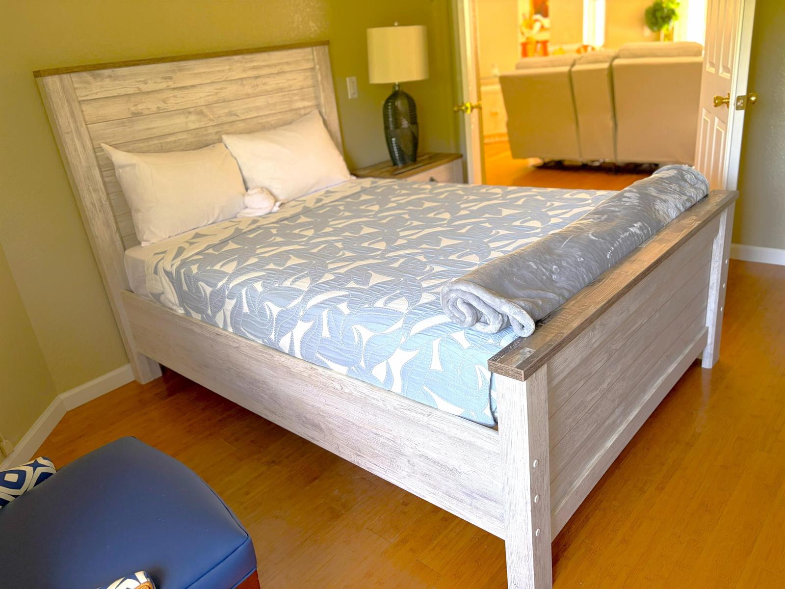 A bedroom features a light wood bed frame, a blue patterned quilt, and hardwood flooring — 7611 N 140th Ave Avenue N, FL 33412, FL