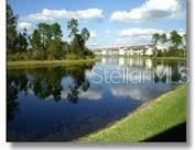 A view of a calm pond with trees on the left and houses in the distance — 5270 HYLAND HILLS AVENUE UNIT 1722, SARASOTA, FL