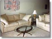 A living room features a beige sofa, a matching loveseat, and an oval glass coffee table — 5270 HYLAND HILLS AVENUE UNIT 1722, SARASOTA, FL