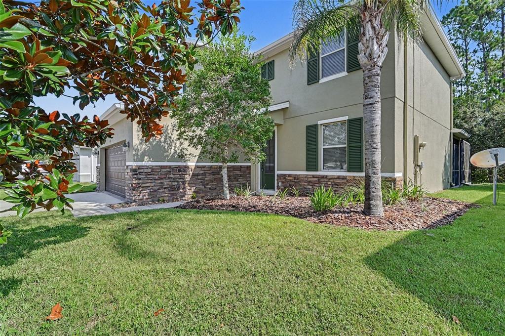 A two-story house with a stone veneer base, green shutters, and a palm tree — 65 PERGOLA PLACE, ORMOND BEACH, FL