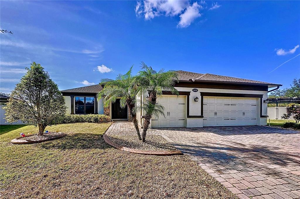 A single-story house with a paved driveway, two-car garage, and a palm tree in front — 5121 APPENINE LOOP W, ST CLOUD, FL