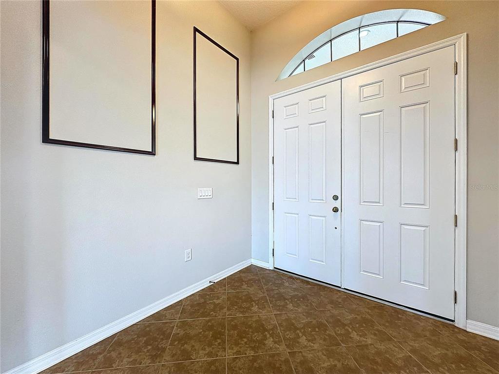 An entryway features tiled flooring, double front doors, and two rectangular wall frames — 5121 APPENINE LOOP W, ST CLOUD, FL