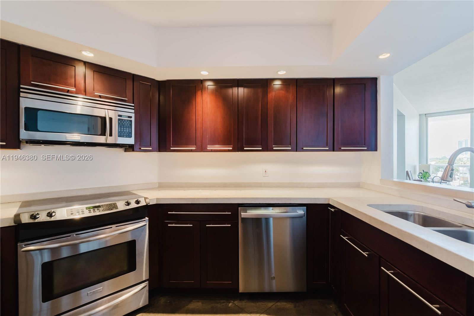 A kitchen features dark wood cabinetry, stainless steel appliances, and light-colored countertops — 1900 Sunset Harbour Dr # 703, Miami Beach FL 33139, MIAMI BEACH, FL