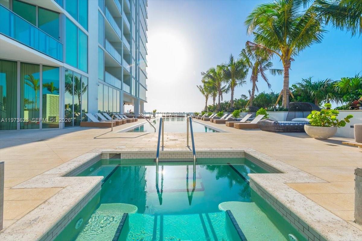 A modern outdoor swimming pool and hot tub area with lounge chairs and palm trees — 2900 NE 7th Ave # 3004, Miami FL 33137, MIAMI, FL